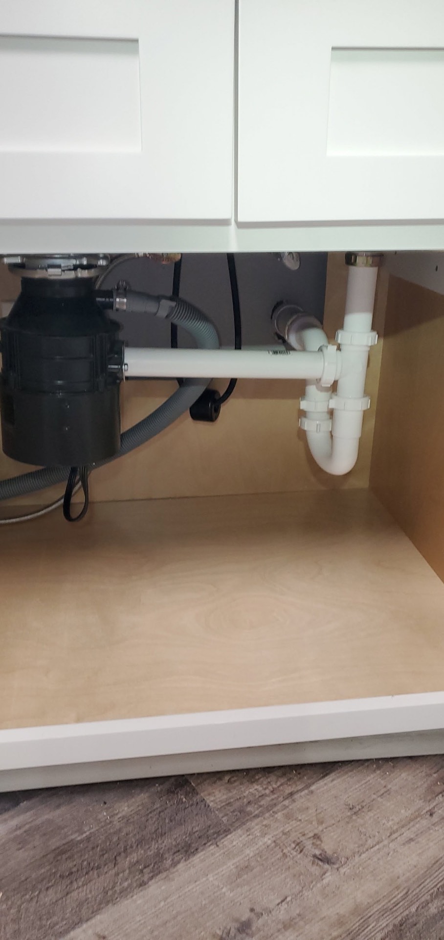 Neatly installed sink drain, P-trap and garbage disposal plumbing