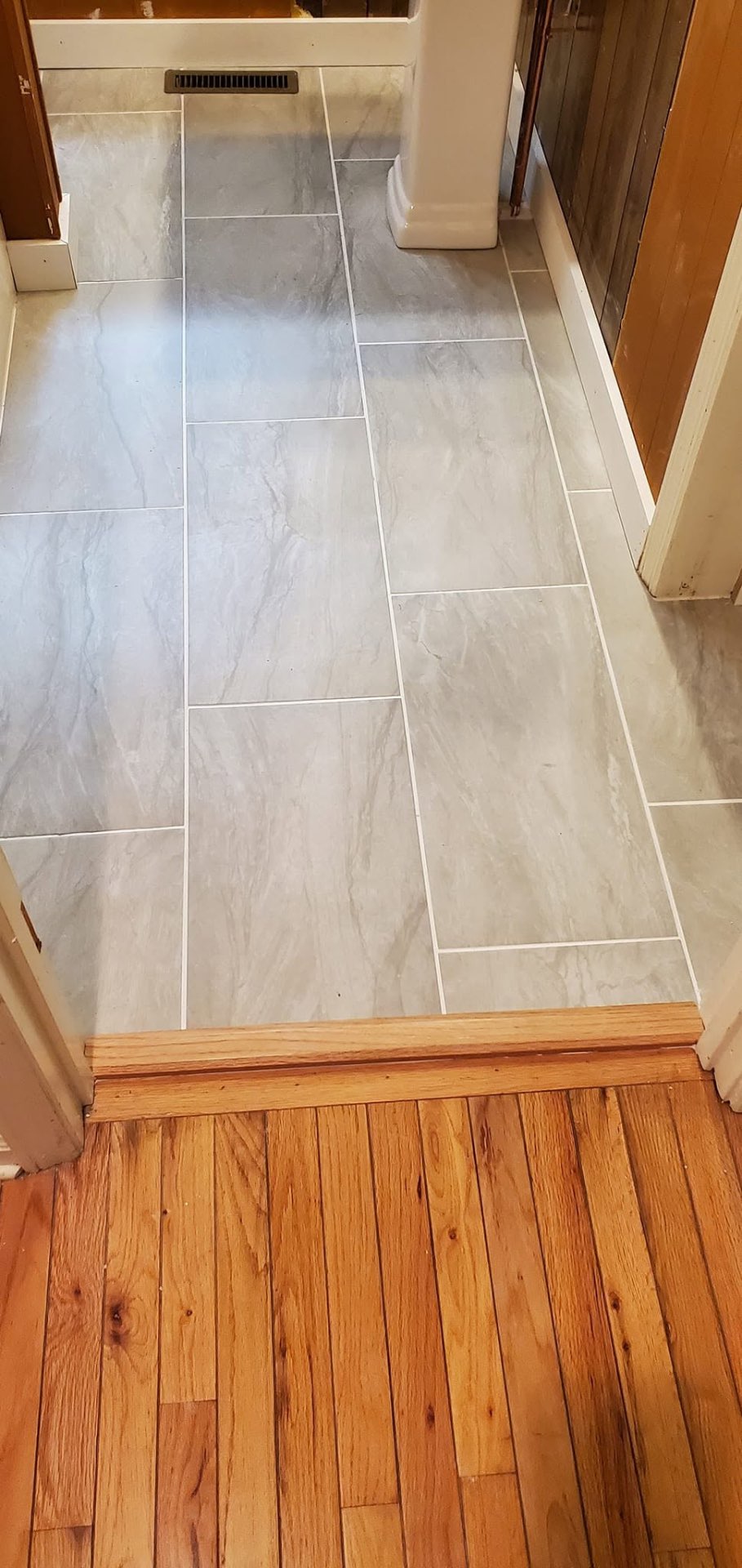 Large-format gray tile floor with clean grout lines and hardwood transition