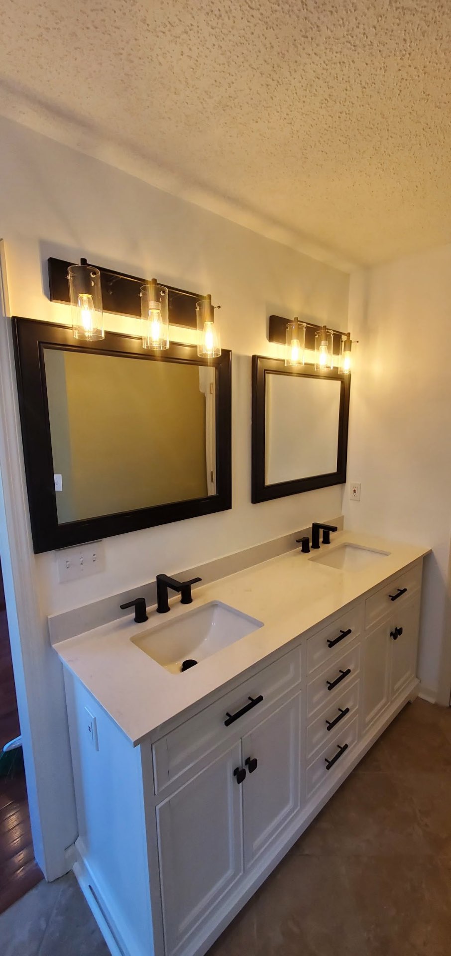 Double bathroom vanity with quartz top, black fixtures, mirrors and new lighting