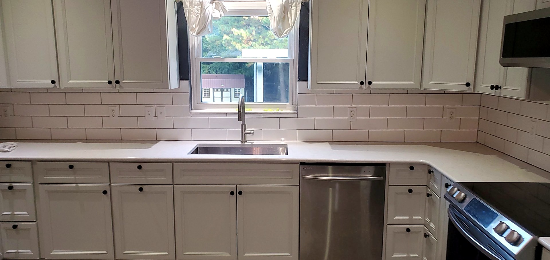 Kitchen update with white shaker cabinets, white quartz counters, subway tile backsplash with dark grout, undermount sink and stainless steel appliances