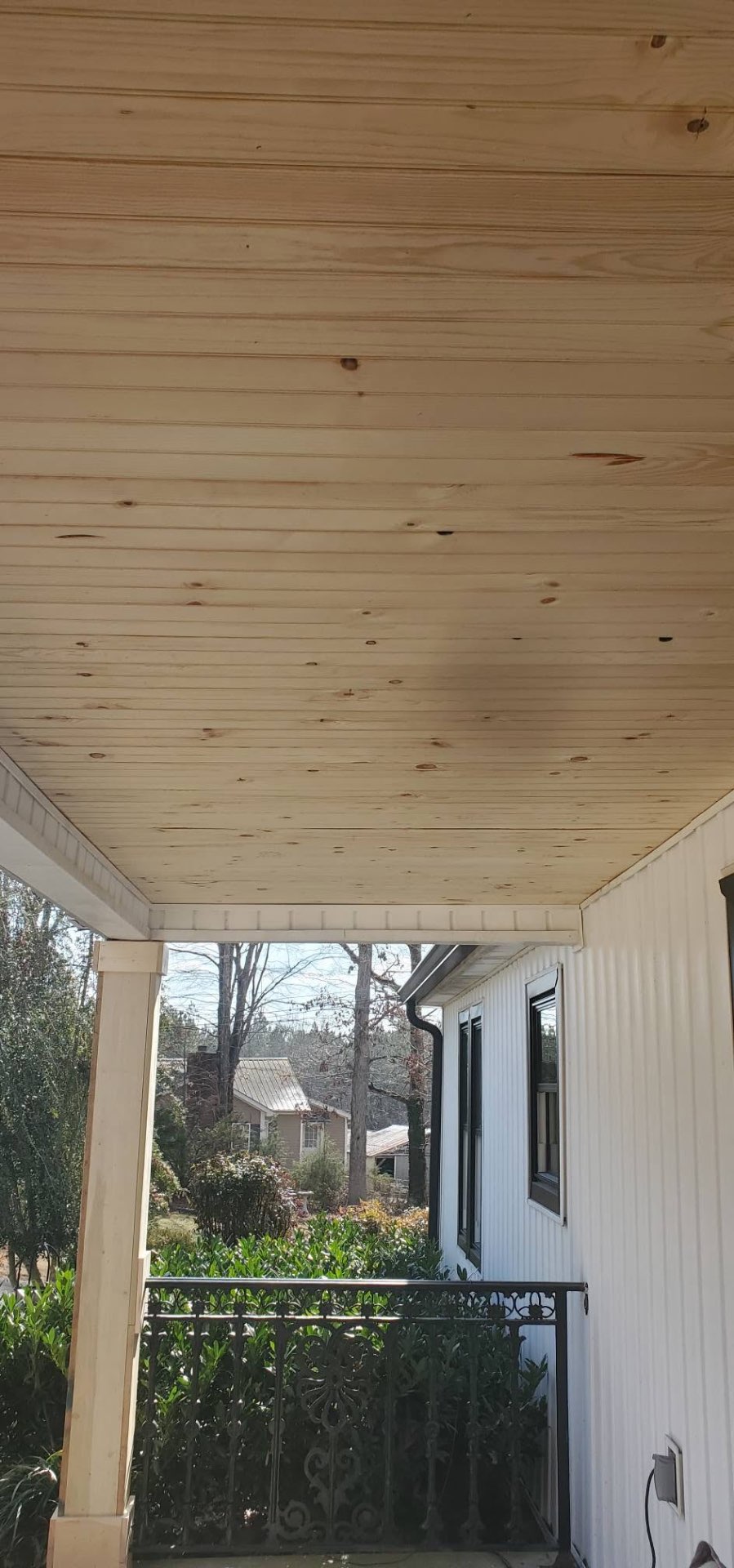 Tongue-and-groove wood ceiling installed on a covered porch with new trim and support post