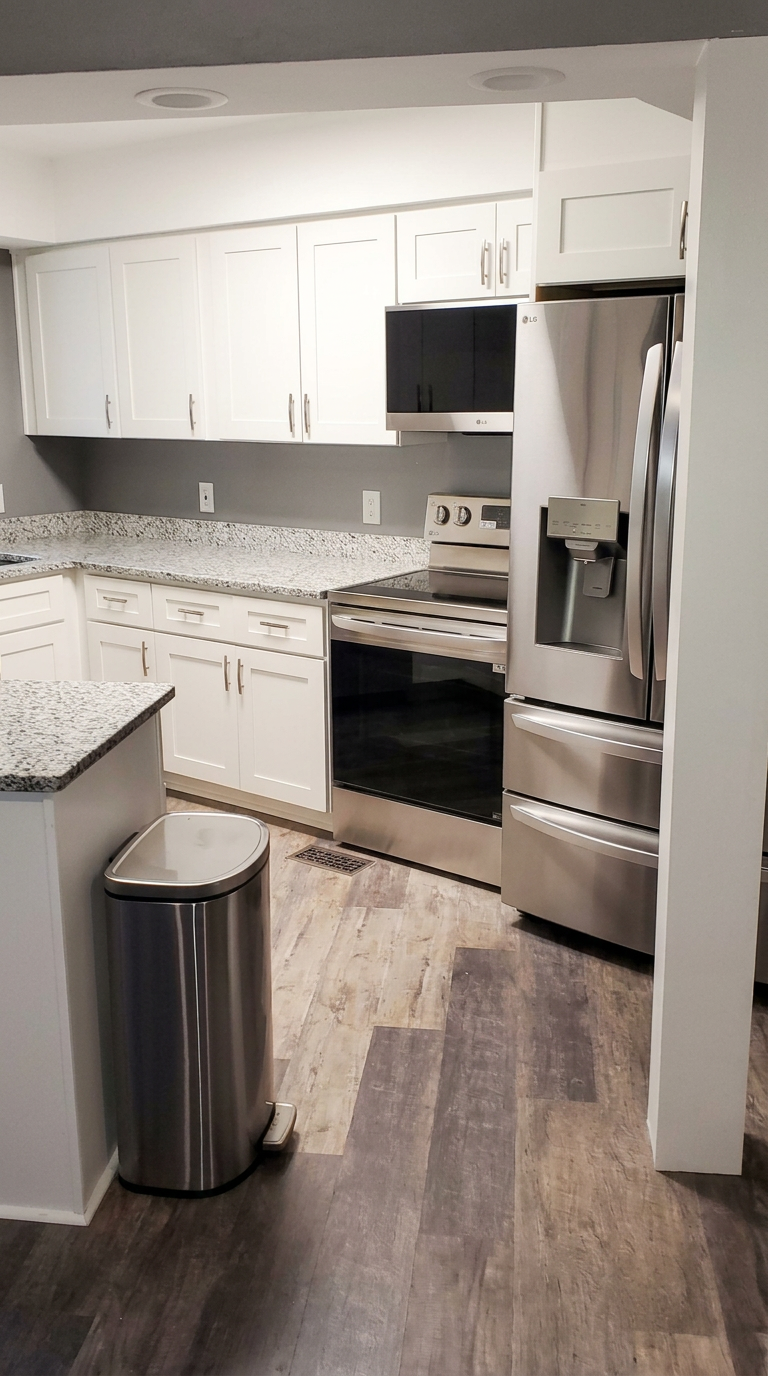 Updated kitchen with white shaker cabinets, granite counters, stainless steel appliances and plank flooring