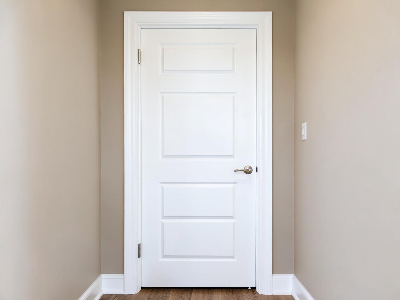 Newly installed white six-panel interior door with fresh white trim and nickel lever handle