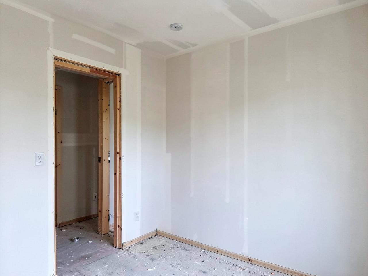 Room with newly hung and finished drywall and wood framing at a doorway opening